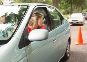 Student driver practicing parallel parking while looking back with instructor in the passenger seat.
